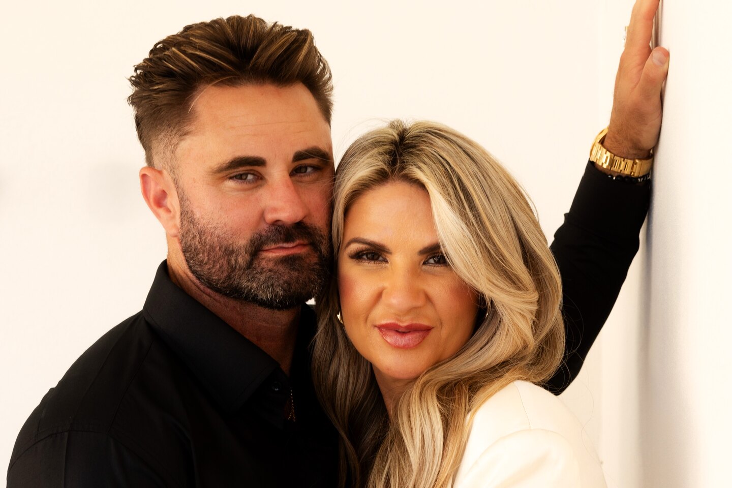 Bree and Mark Gentry, founders of We Are Aligned, cheek to cheek against a soft cream wall, both looking warmly into the camera.