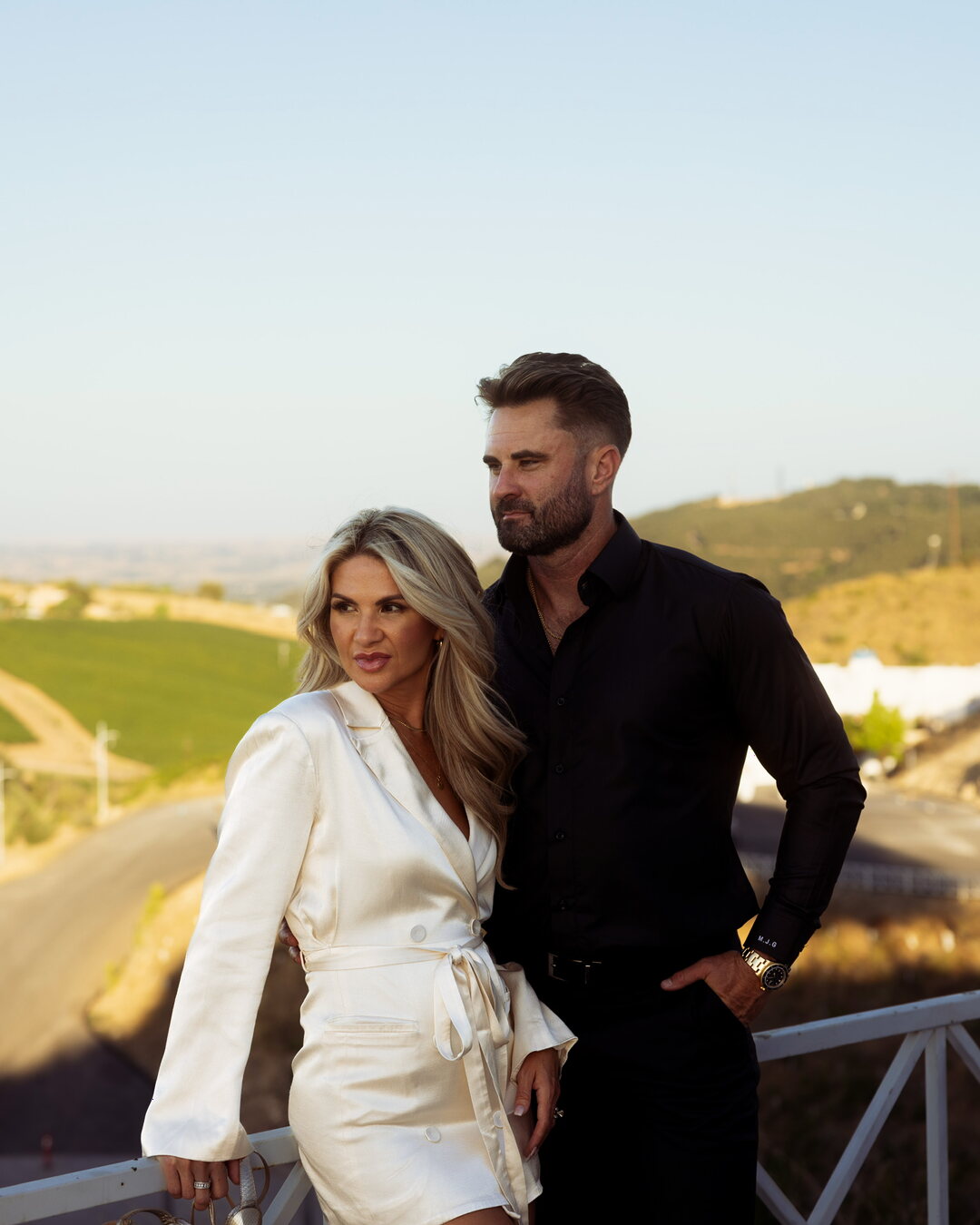 A couple standing together at golden hour looking out over open hills, a longer look forward at the years ahead.